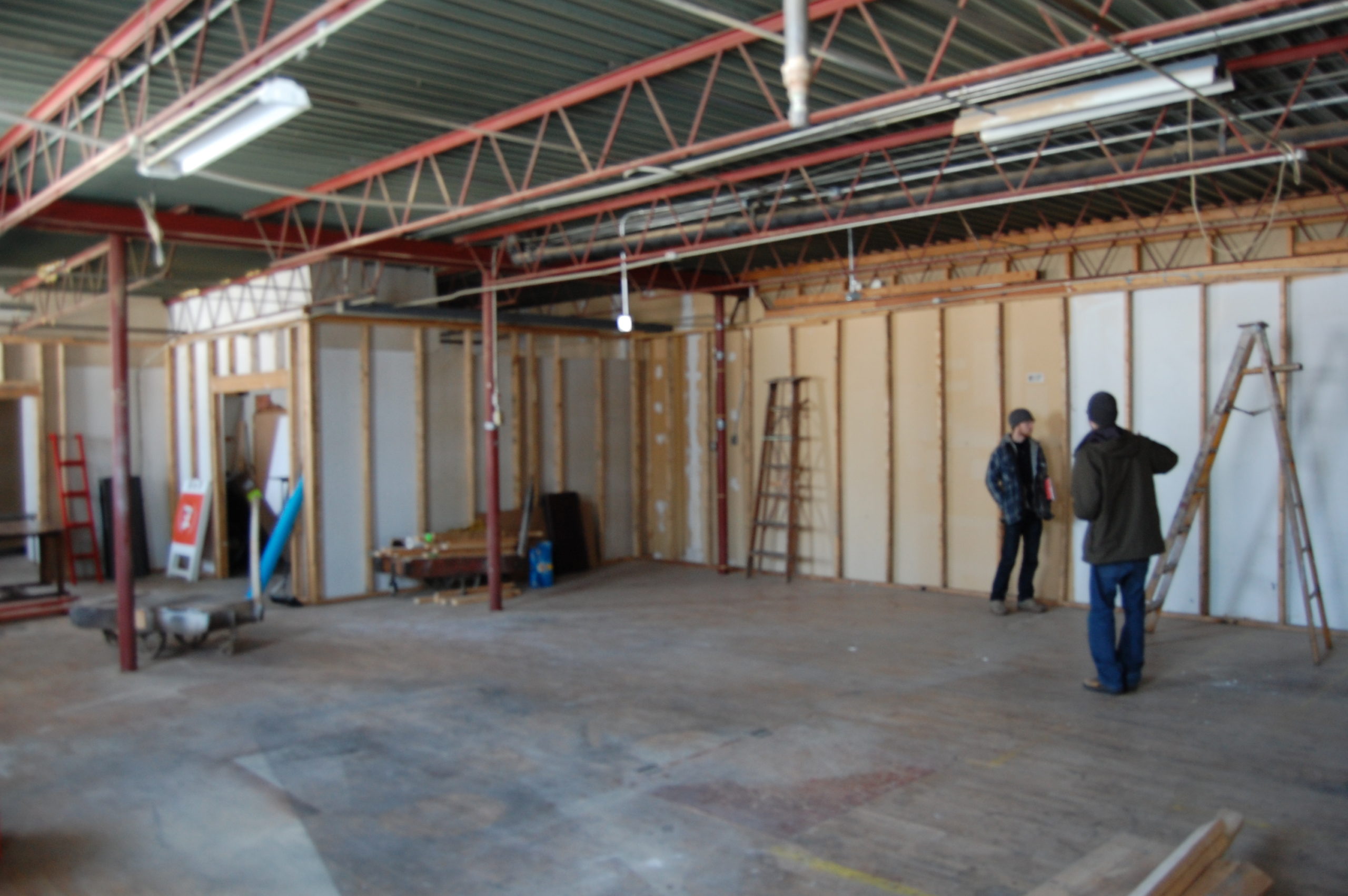 People building walls in an open room. Dinderbeck Studios.