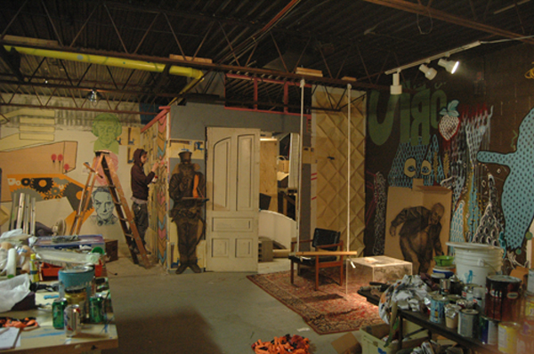 People collaging the walls in an open room. Dinderbeck Studios.