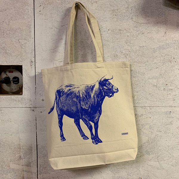 A canvas tote bag with a blue bull screenprinted onto it.